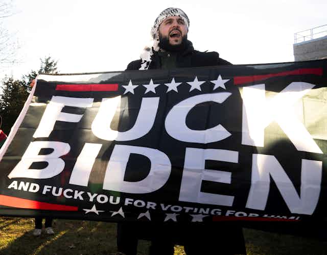 Homme tenant affiche proclamant « Fuck Biden » 