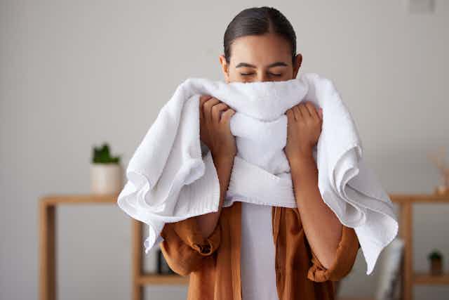 A woman smells a white towel.