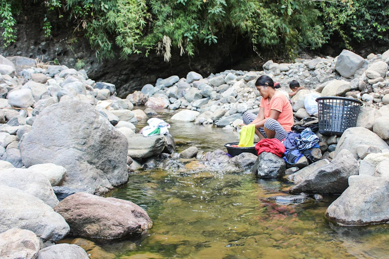 Une femme faisant sa lessive près d'une rivière.