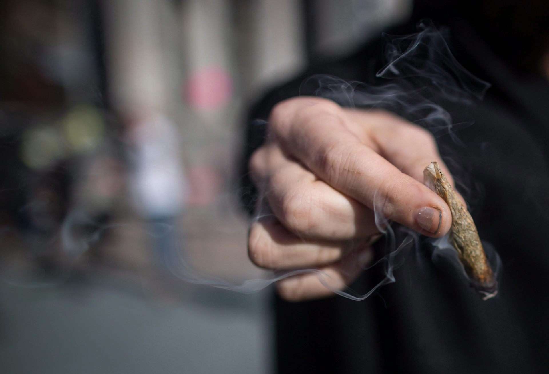 A hand holding a cannabis cigarette