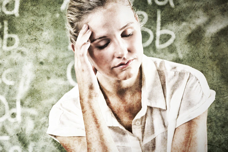 A teacher puts her hand to her temple and looks exhausted.