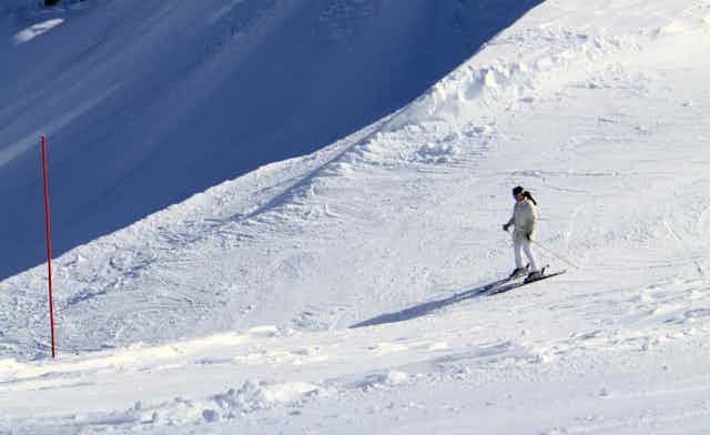 A person stand on skis looking over a sharp drop off at Tahoe Palisades.