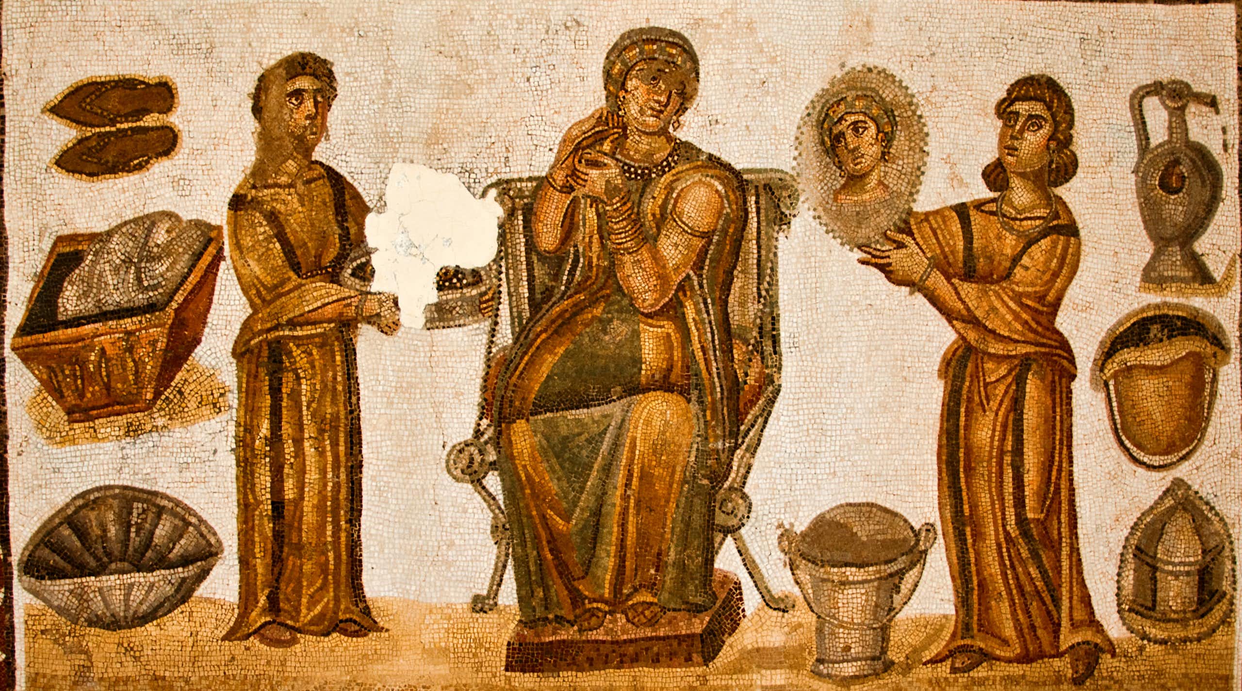 Mosaico que representa a una mujer en el baño con otras dos figuras que la ayudan a arreglarse.