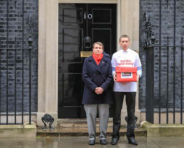 Campaigner Chris Head wearing a tshirt reading 'Post Office Horizon Scandal' stands holding a red box outside 10 Downing Street. 