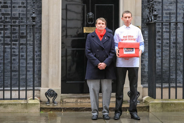 Campaigner Chris Head wearing a tshirt reading 'Post Office Horizon Scandal' stands holding a red box outside 10 Downing Street.