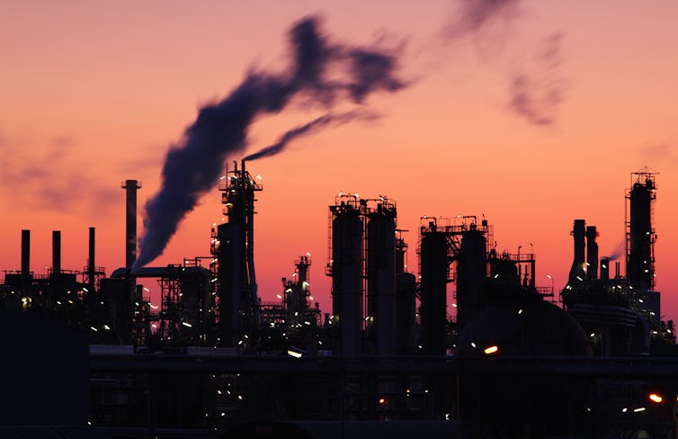 An oil refinery silhouetted against the sky at dusk.