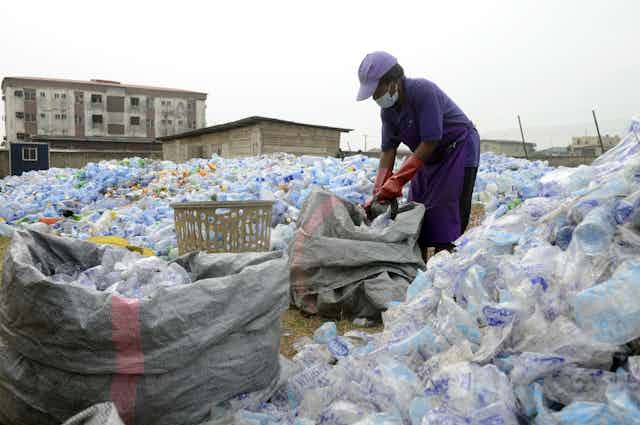 Woman surrounded by plastic bottles she packs into sacks