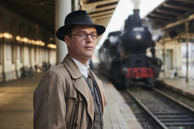 Johnny Flynn as the young Winton at a train station.