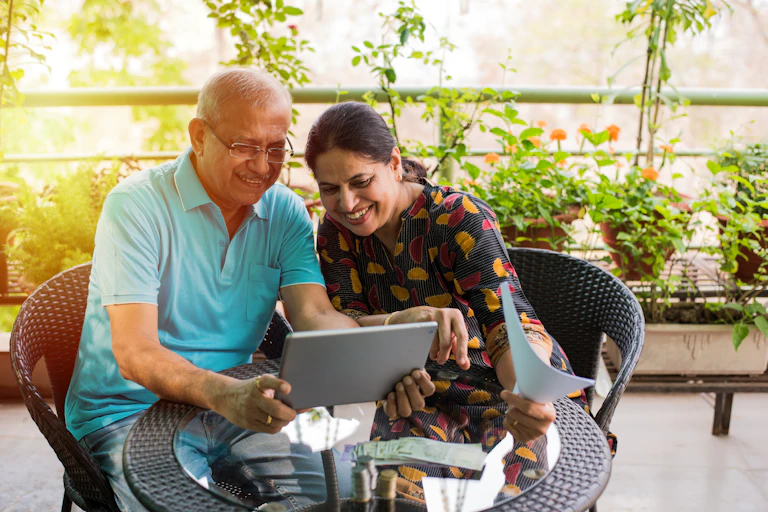 Older couple look at ipad with paperwork.