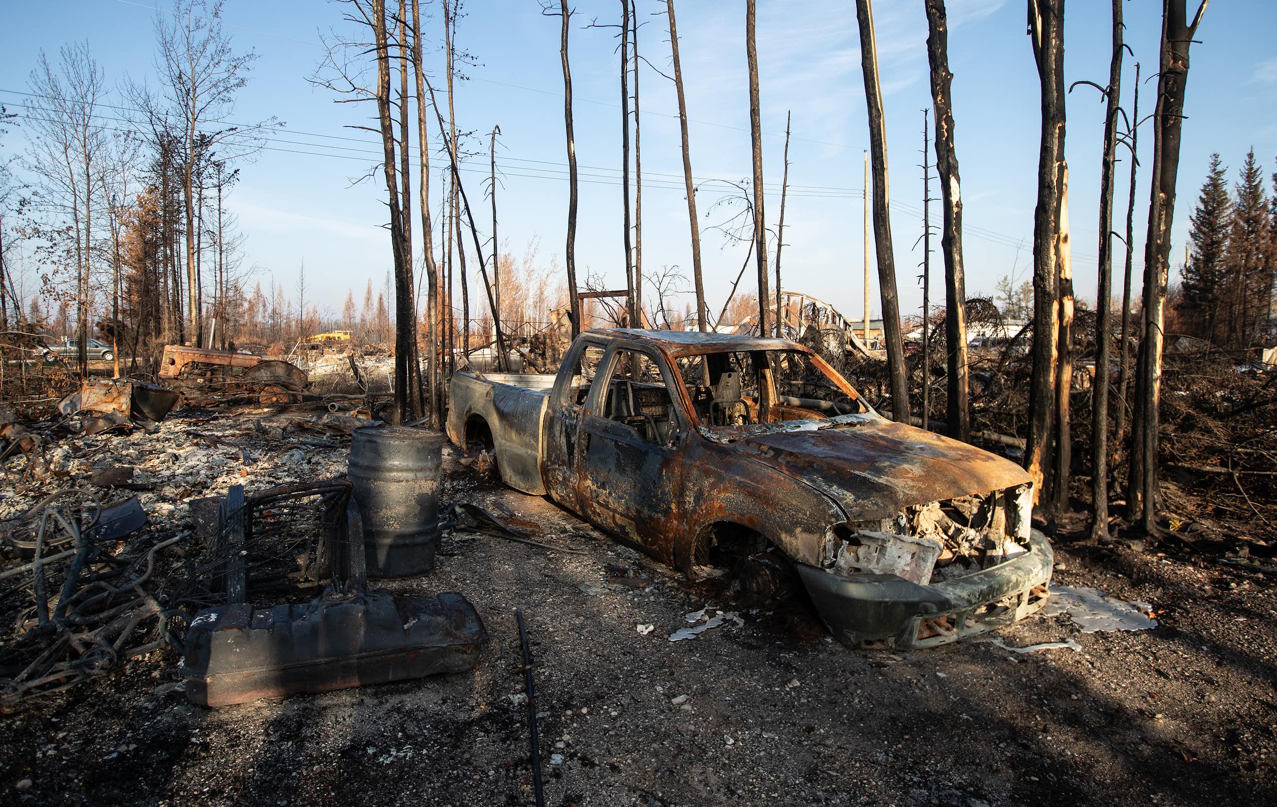 A burned out truck and assorted rubble is seen in the aftermath of a forest fire.
