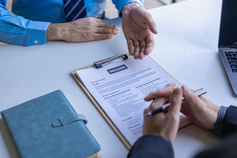 A resume on a table between two people who can only be seen by their arms