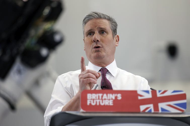 A man addresses a press conference behind a lectern reading 'Britain's future'