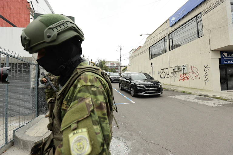 A man in army fatigues looks downward as he stands in an ally.