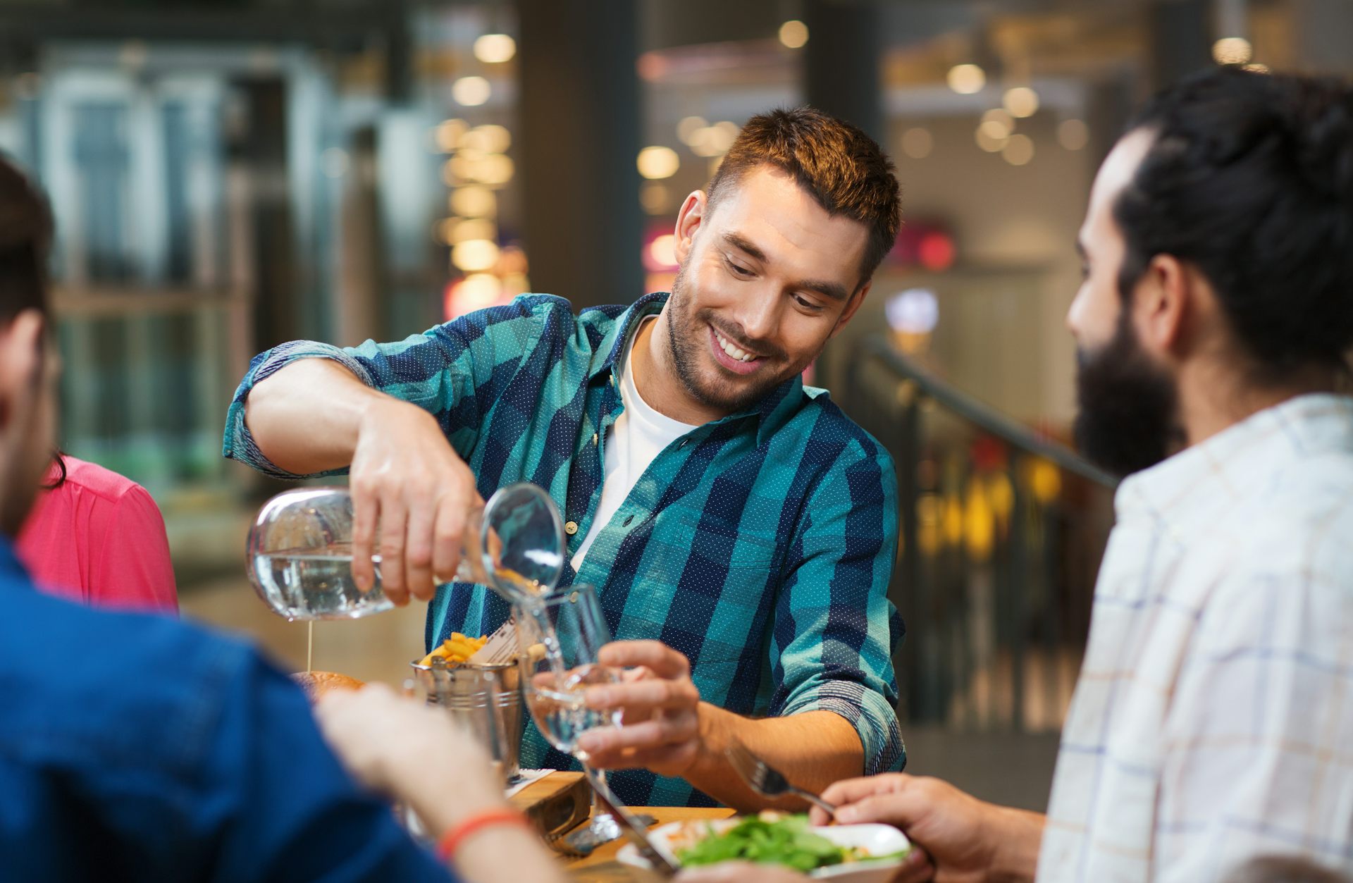 Un jeune homme se sert un verre d’eau à dans un restaurant.