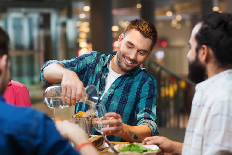 Un jeune homme se sert un verre d’eau à dans un restaurant.