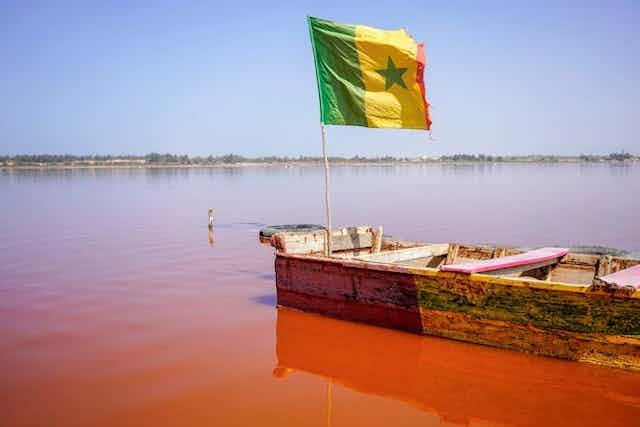 A small wooden boat bearing a flag, in water with a reddish colour.