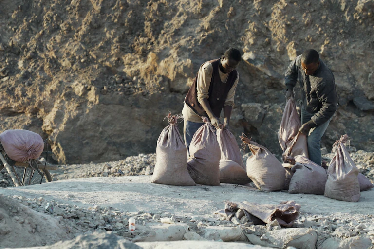 Two men load ore into sacks.