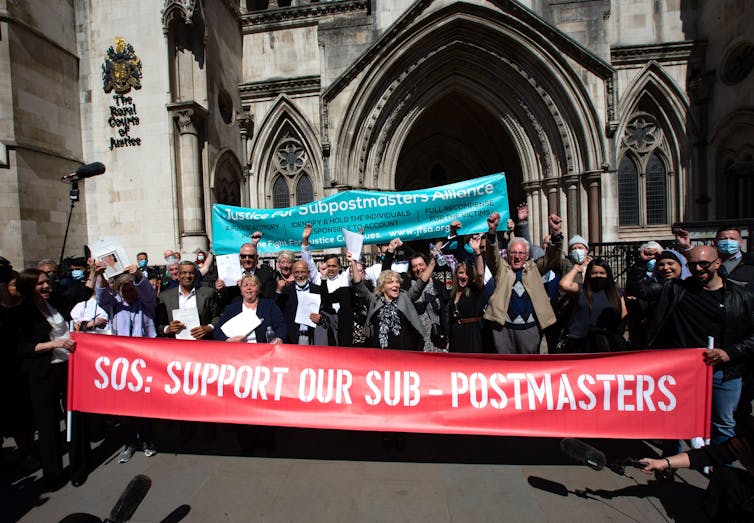 A group of people with banners outside the Royal Courts of Justice.