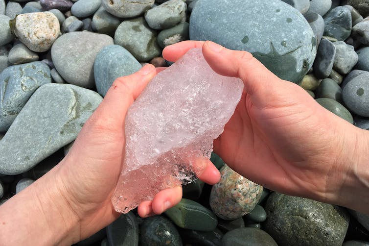 artist's hands holding small chunk of glacial ice