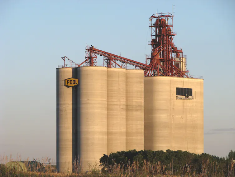 A tall concrete grain elevator with a sign hanging on it that says 'Pool'