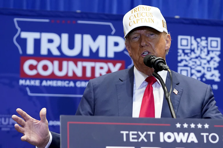 A man in a white cap speaks into a microphone on a lectern