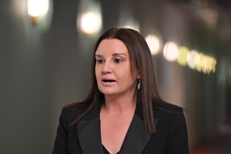 A woman in a black blazer talks