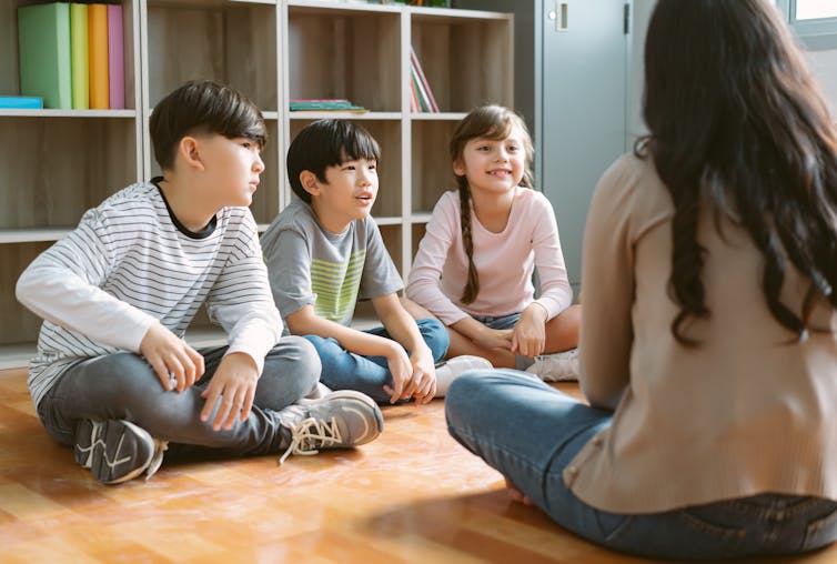 children sitting on floor with teacher