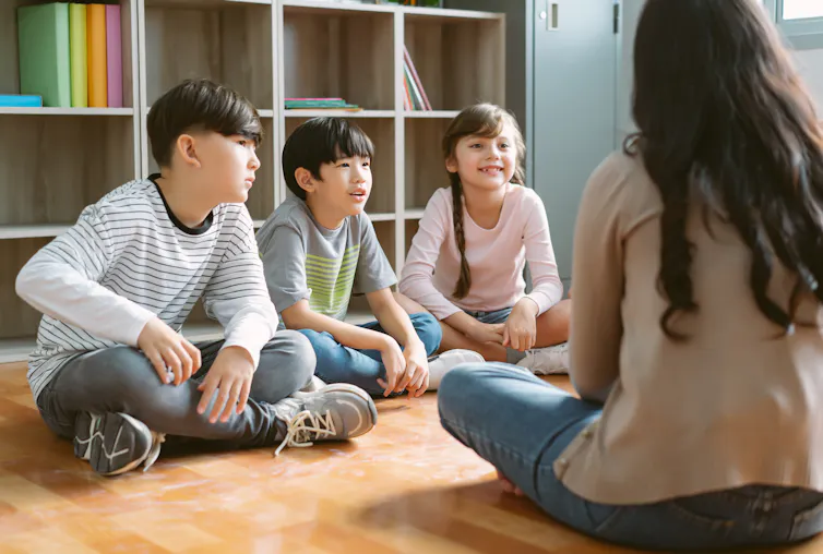 children sitting on floor with teacher