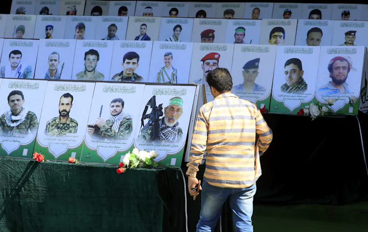 A man walks past placards with the portraits of hundreds of Houthi rebel fighters killed during Yemen's ongoing civil war.
