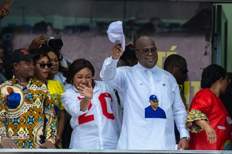 A man in a white shirt stands behind a group of women.