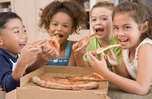 Children sharing a pizza.