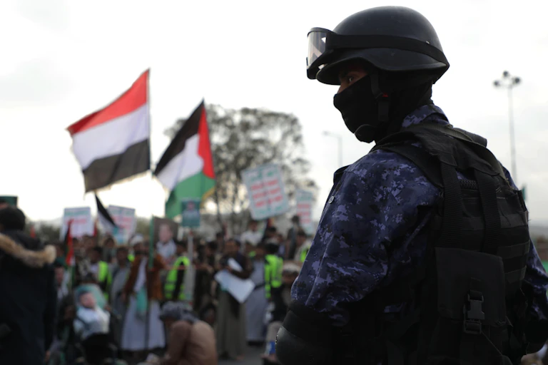 A man in military garb stands in front of protesters.