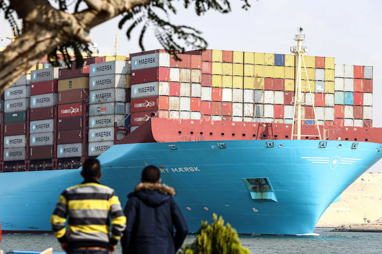 Two boys gaza at a container ship in the Suez Canal