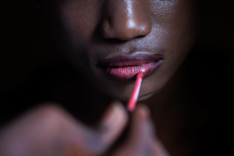 Young person applies lipstick.