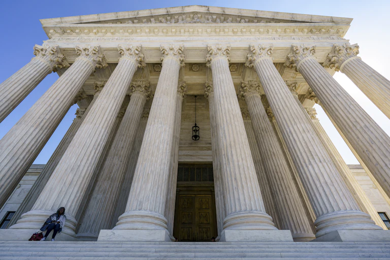 A large white-columned building, seen from steps below it.