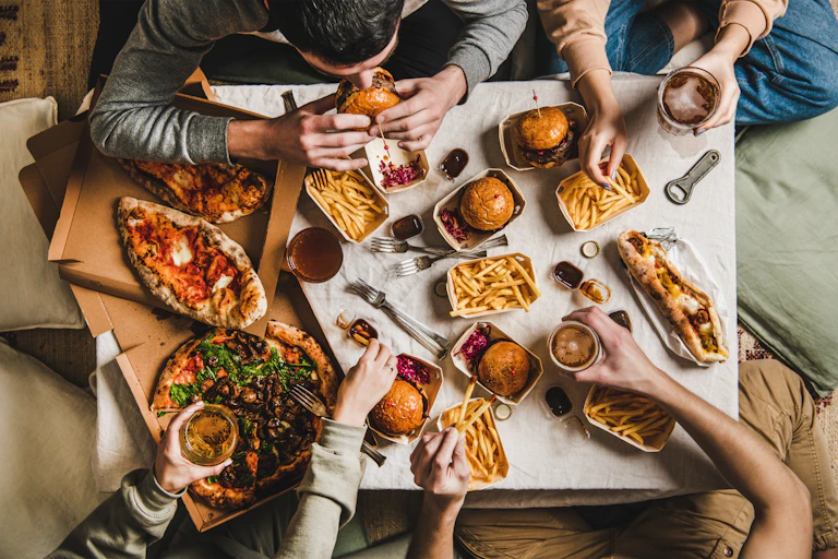 A birds eye view of people sitting around a table eating fast food.