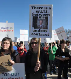 A person seen with sign 'there is a wall between me and my contract.'