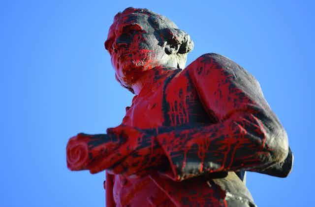 A Captain Cook statue splashed with red paint.