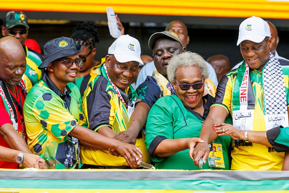 People wearing green, yellow and black clothing join hands, smiling
