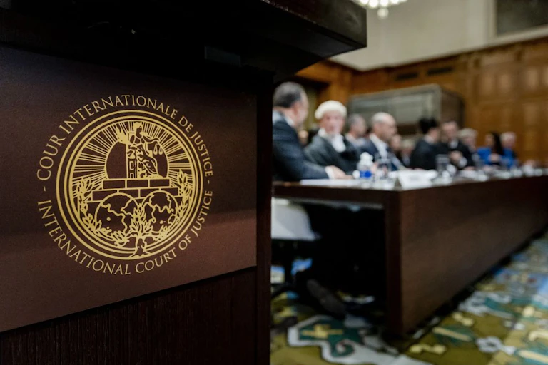 A logo of the International Court of Justice in the foreground with a silhoutte of judges sitted in the background