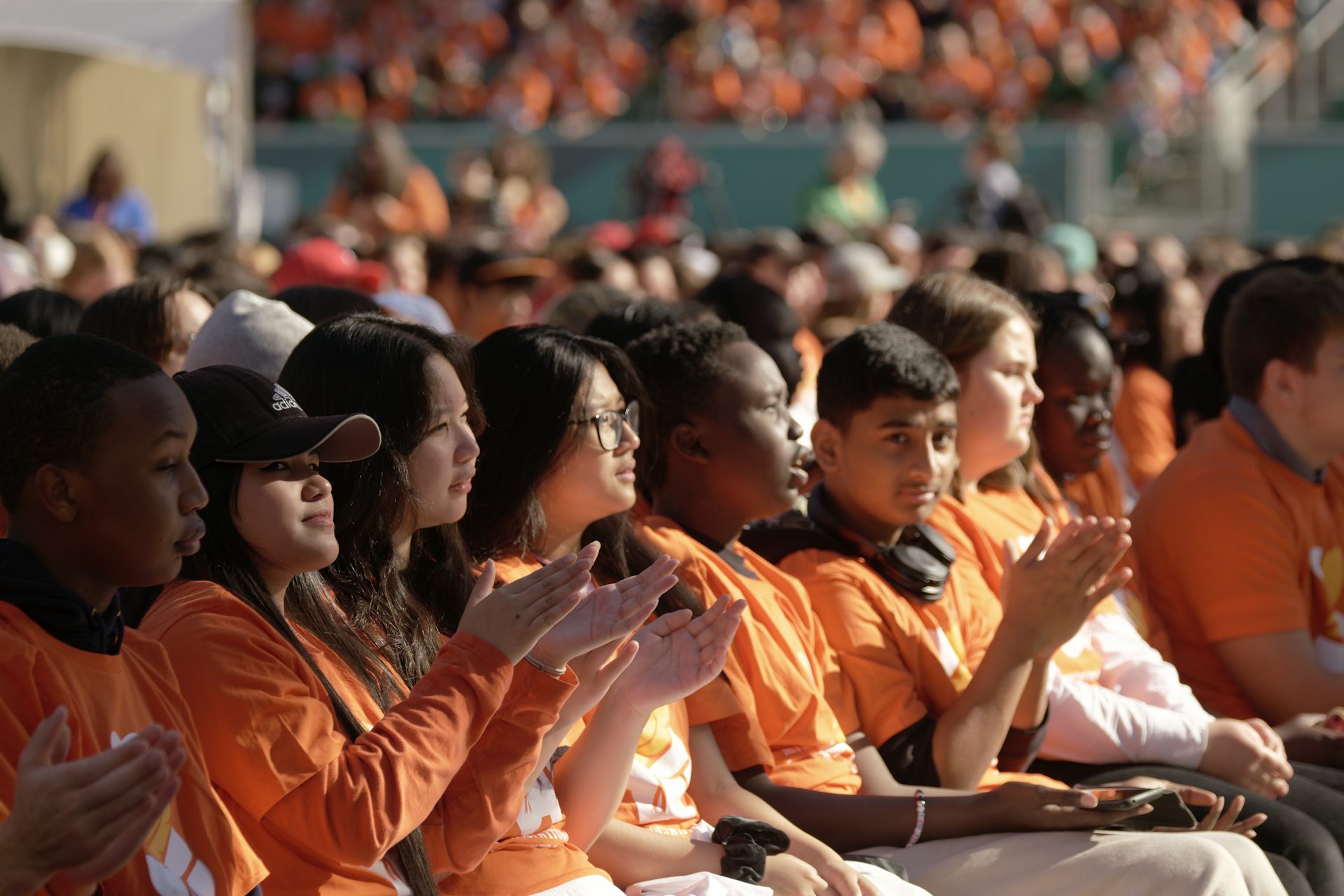Students in orange shirts applaud.