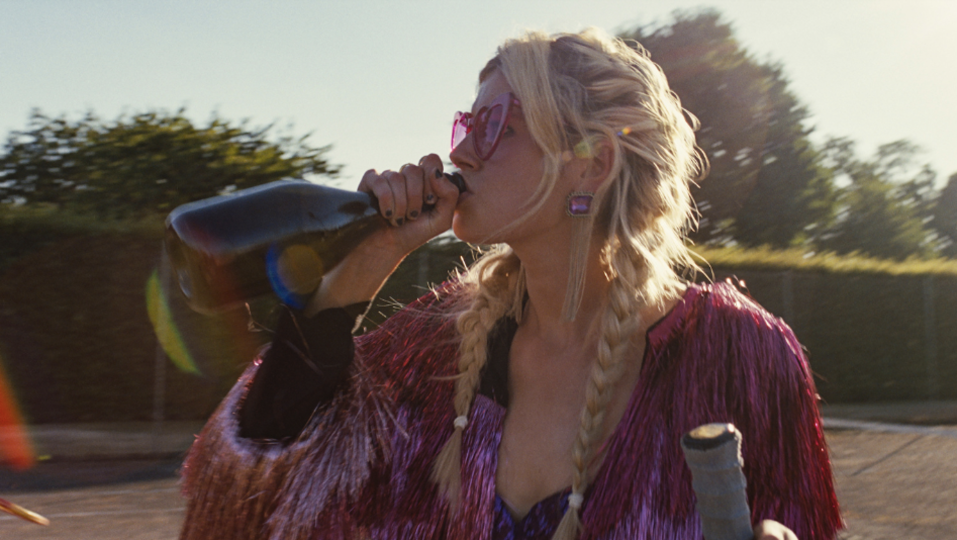 Alison Oliver as Venetia drinking from a champagne bottle