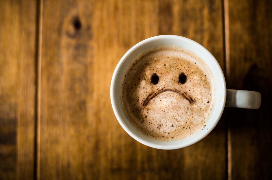 A cup of coffee with a sad face emoji.