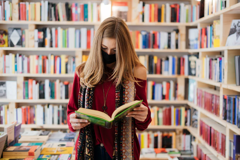 a woman reading in a bookshop while wearing a COVID mask.