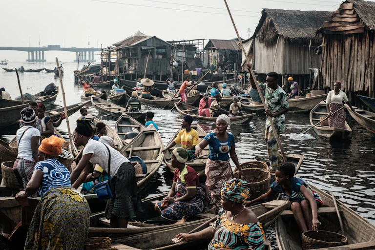 Women in canoes gather in groups close to houses on stilts.