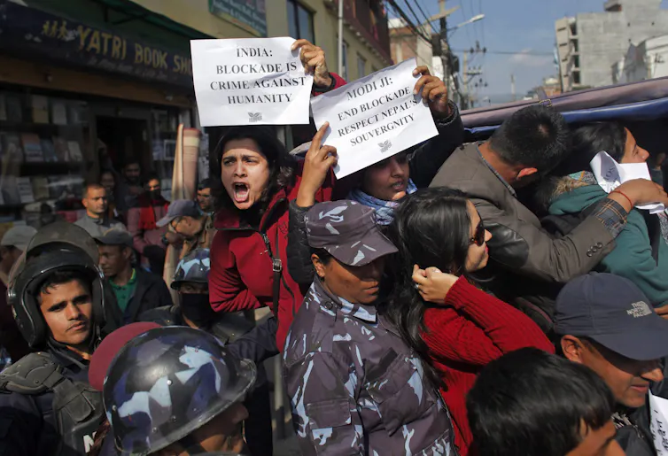 People holding signs shout as they are detained by police.