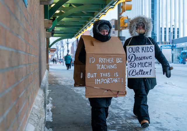 People in parkas seen with signs including 'our kids deserve so much better.' 