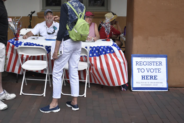 A voter registration table with red-white-and-blue design but no partisan markings.