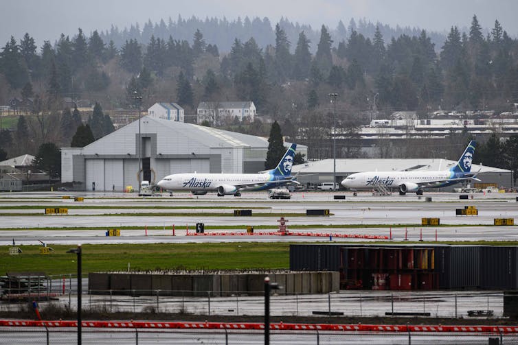 Two planes sit parked on the tarmac at an airport.