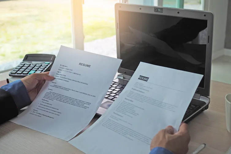 A person holds two resumes up beside one another
